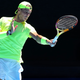 A photo of tennis player Rafael Nadal hitting a ball on a court.
